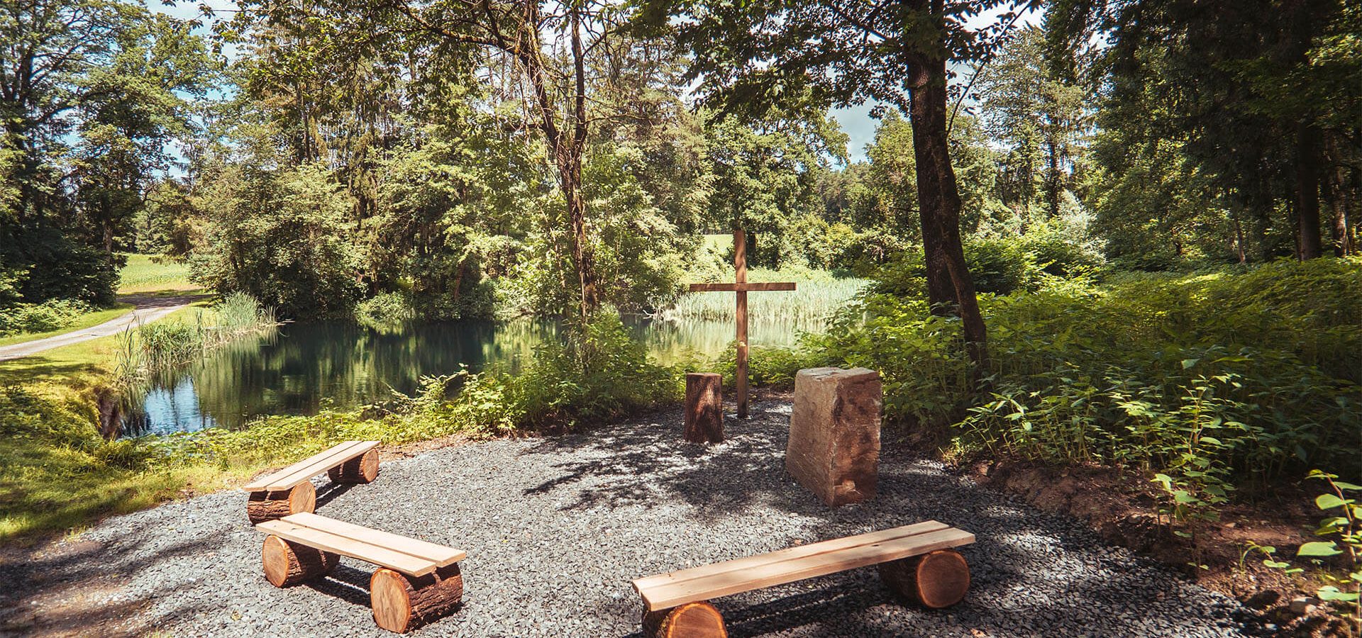 paxnatura Naturbestattung - Waldfriedhof Wundschuher See bietet einen Andachtsplatz mit einem malerischen Teich im Hintergrund